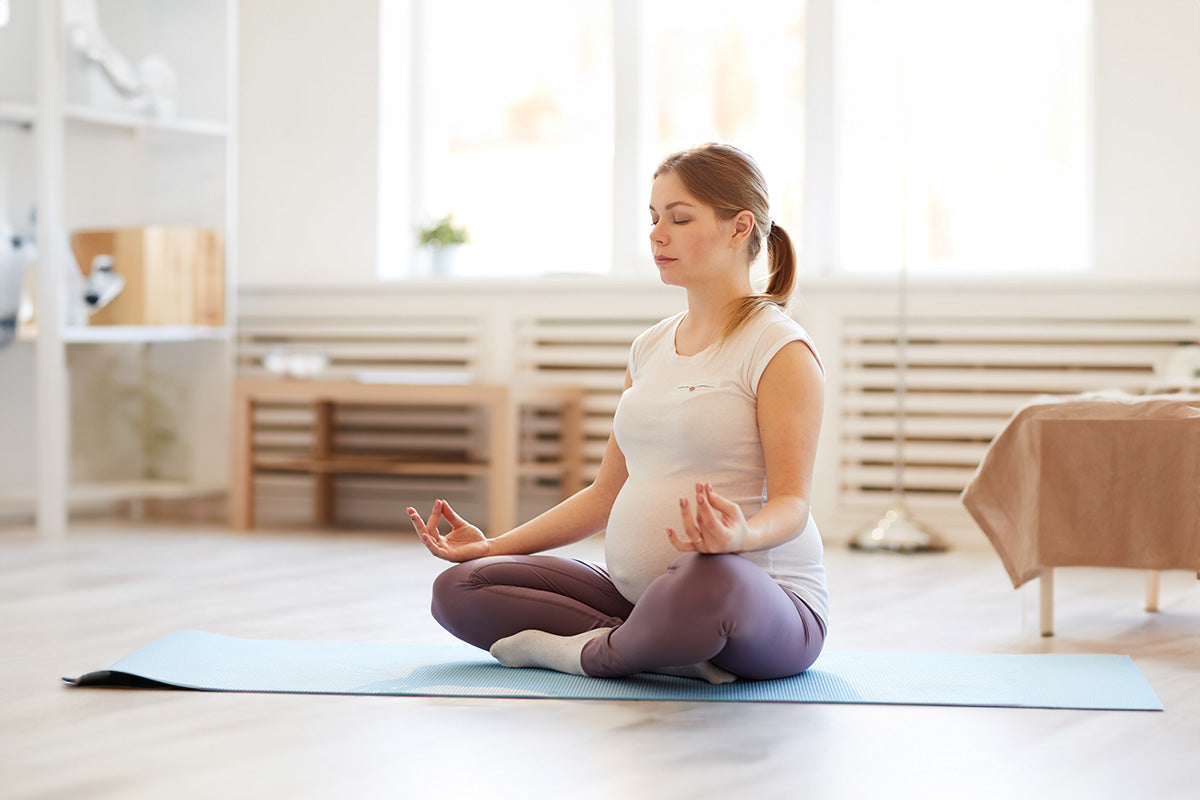 Pregnant woman practicing yoga in her home.