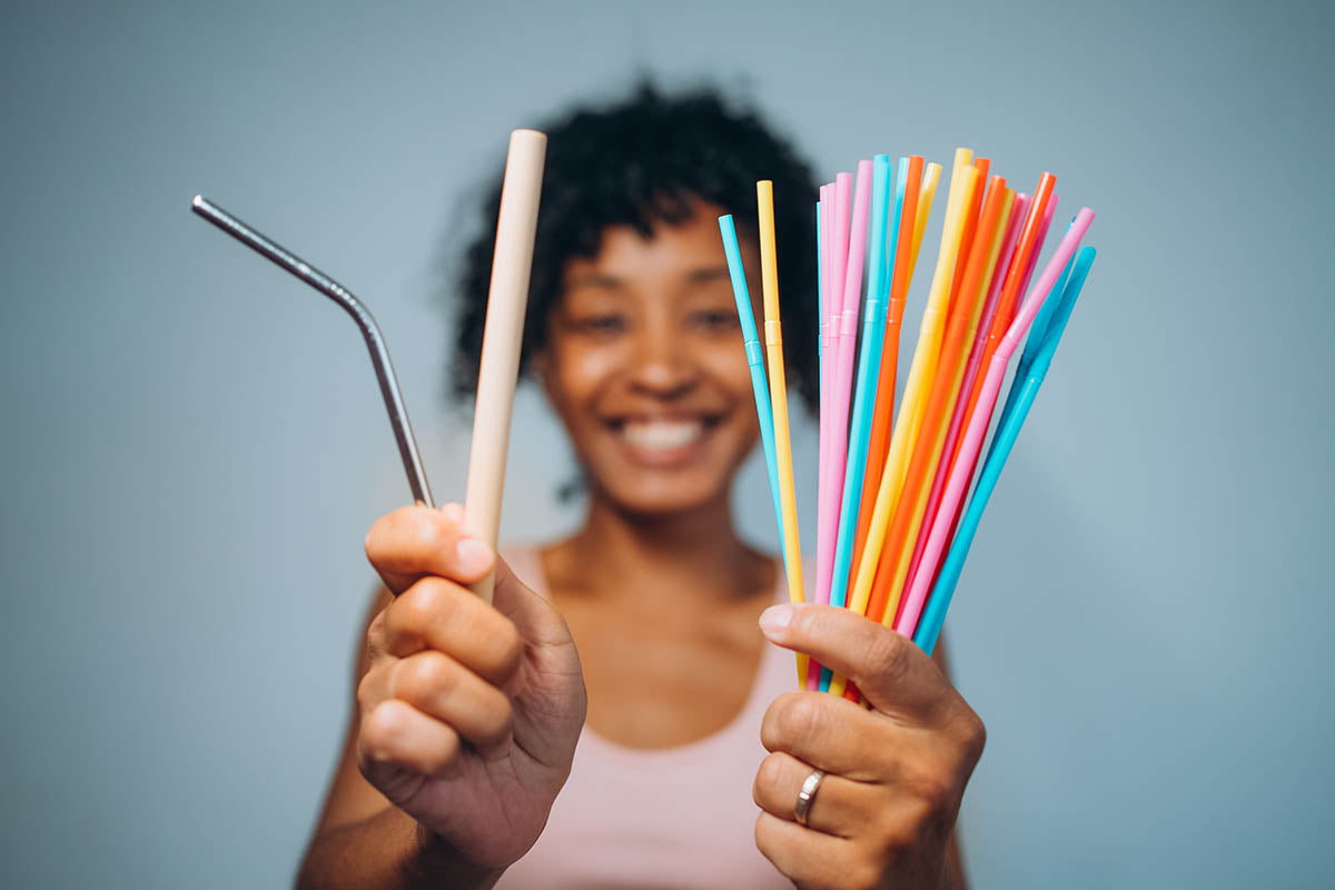 Young, attractive female model holding plastic straws, and plastic straw alternatives.