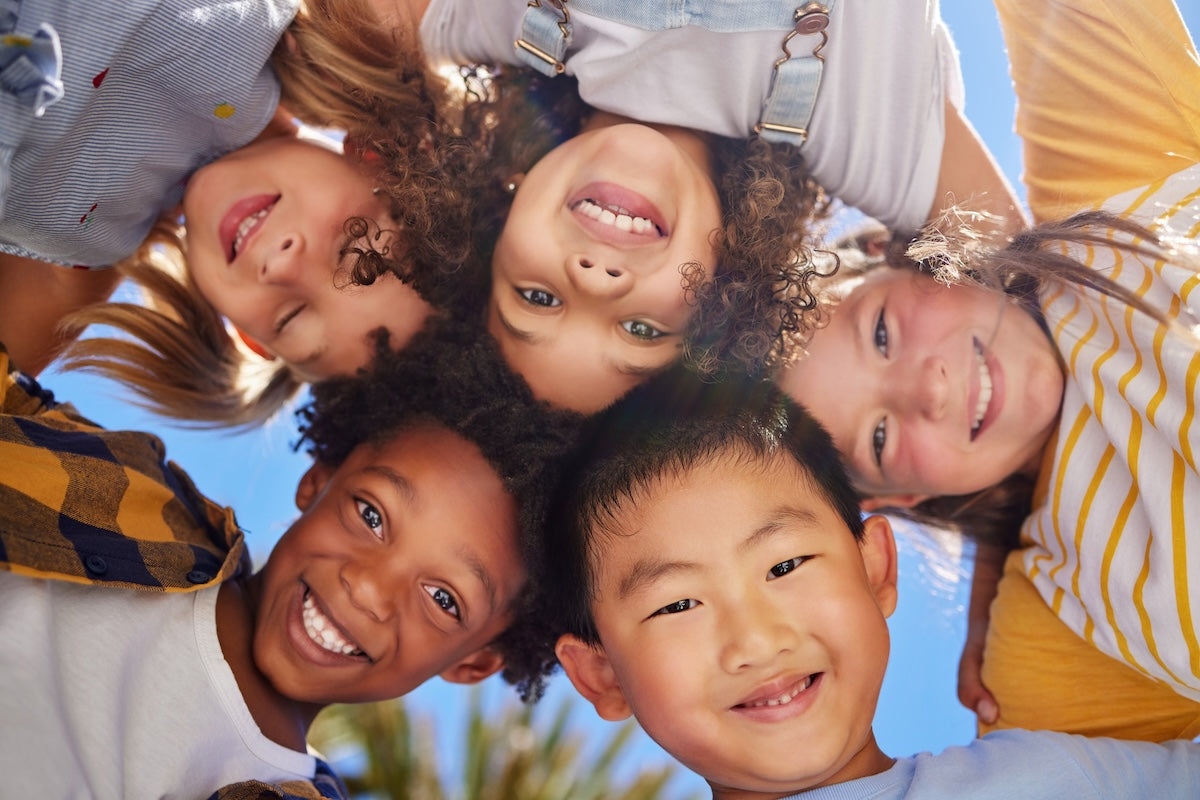 Multiracial group of smiling children, looking down at the camera. 