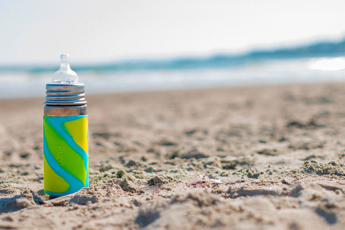 Closeup of Pura Stainless Bottle lying on the beach.