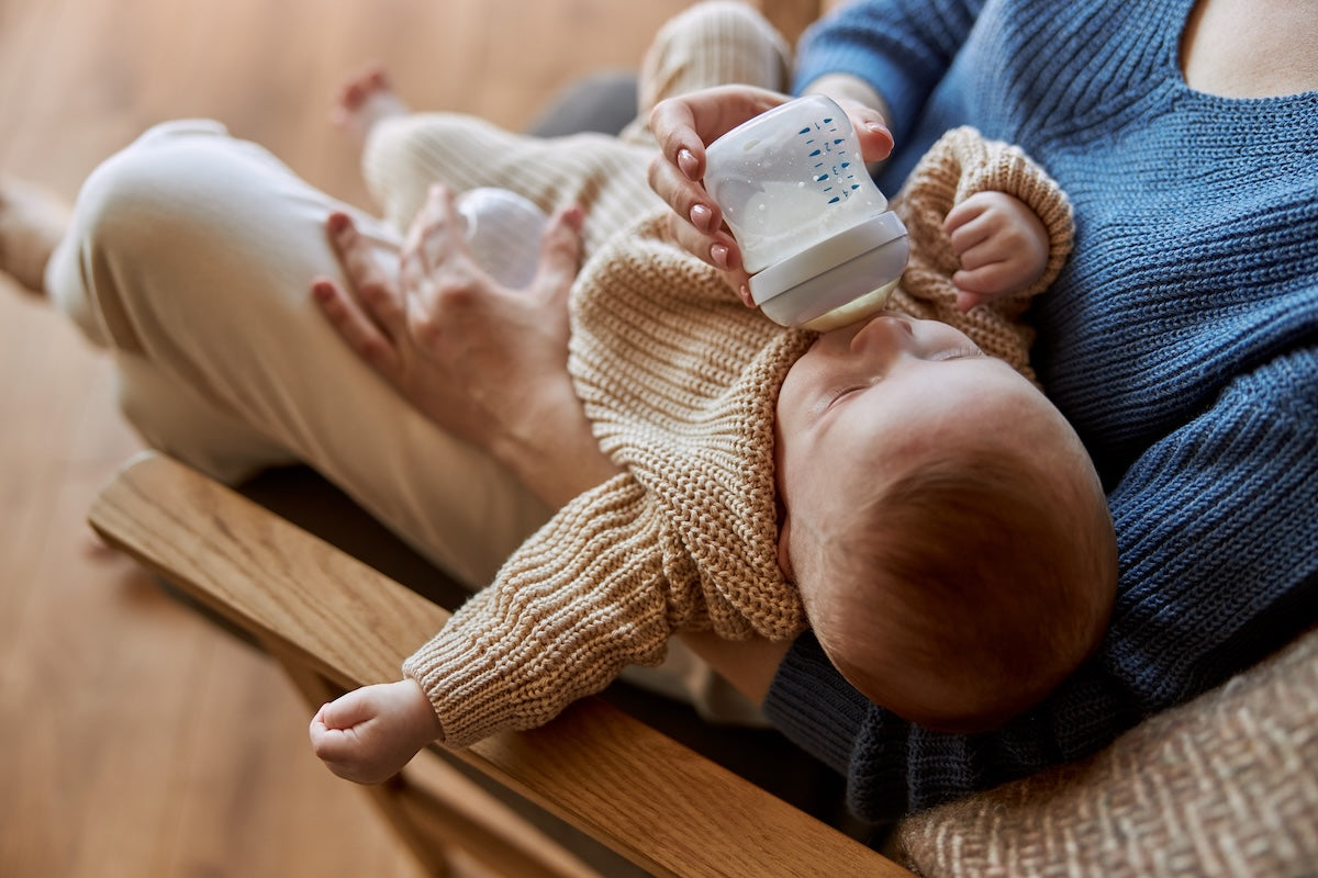 Mother feeding caucasian infant with a plastic baby bottle