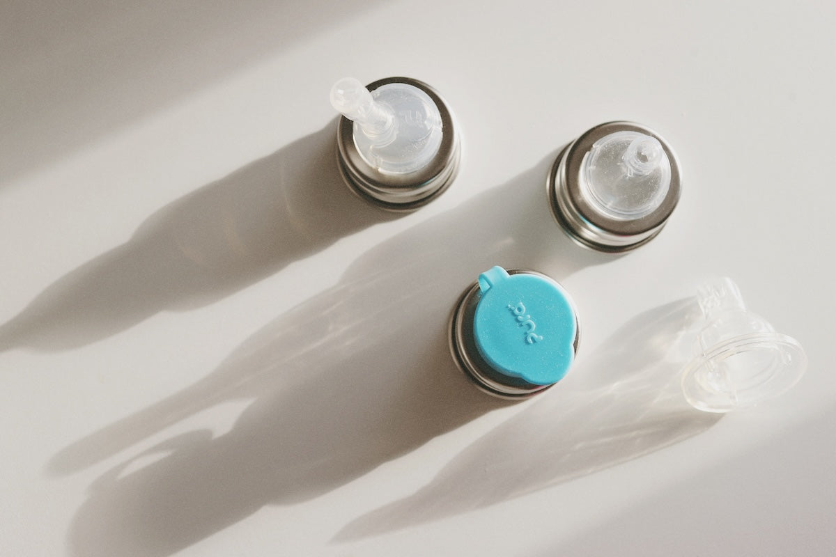 Pura Stainless steel water bottle lids and silicone components on a counter