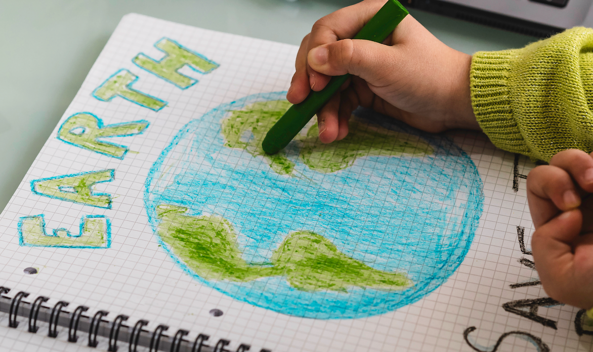 A child drawing a “Save the Earth” poster for Earth Day.