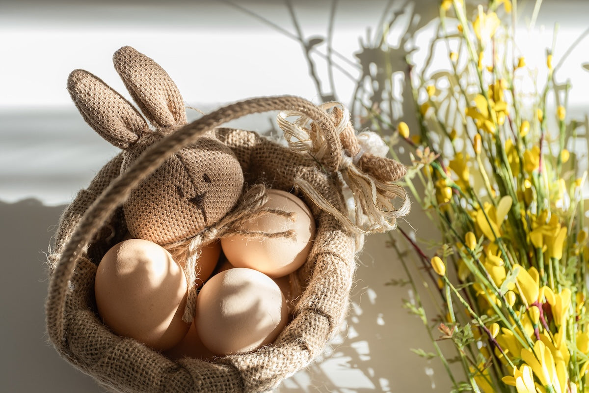 Eco-friendly Easter basket with fresh eggs and a stuffed bunny.