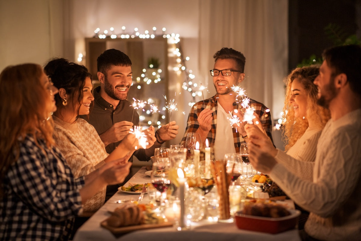 A group of friends celebrating New Year’s together at dinner with sparklers
