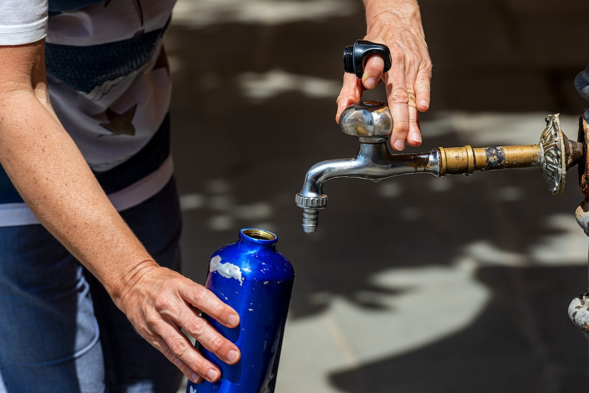 Caucasian woman refilling an old stainless steel water bottle